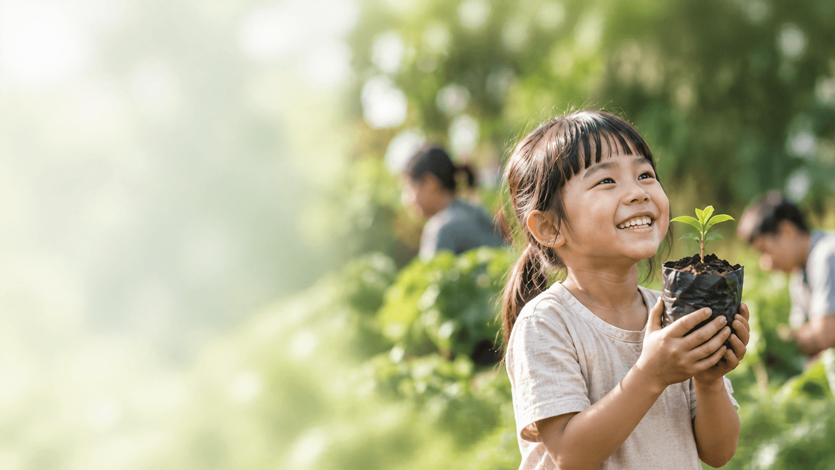 Em nhỏ mỉm cười ôm cây non xanh giữa không gian thiên nhiên